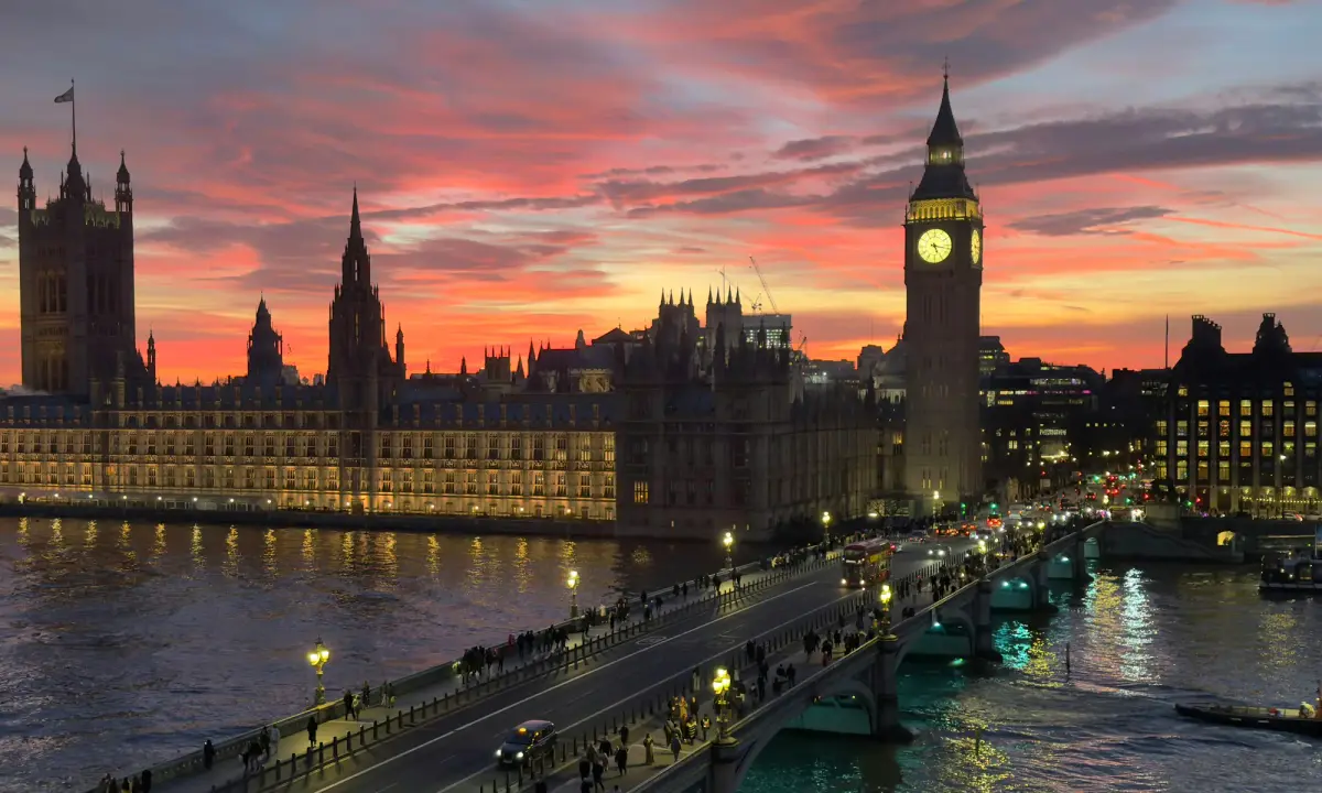 O Big Ben e o Parlamento britânico ao entardecer, vistos de cima, com a ponte de Westminster sobre o Tâmisa